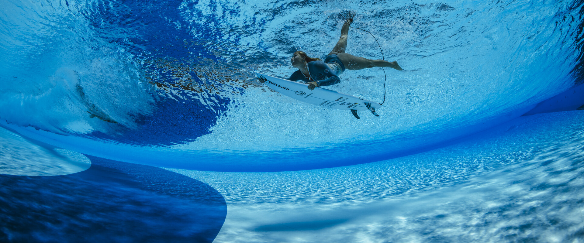 Im derzeit gr&ouml;&szlig;ten Wellenpark Europas kannst du das ganze Jahr &uuml;ber surfen. Das Bild zeigt eine Surferin beim Duckdive unter eine k&uuml;nstlichen Welle hindurch.